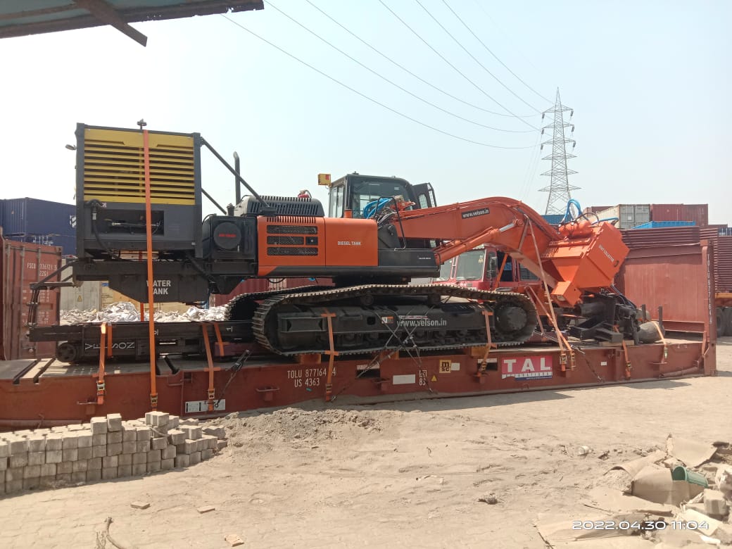 Excavator with drilling unit secured on a flat-rack container