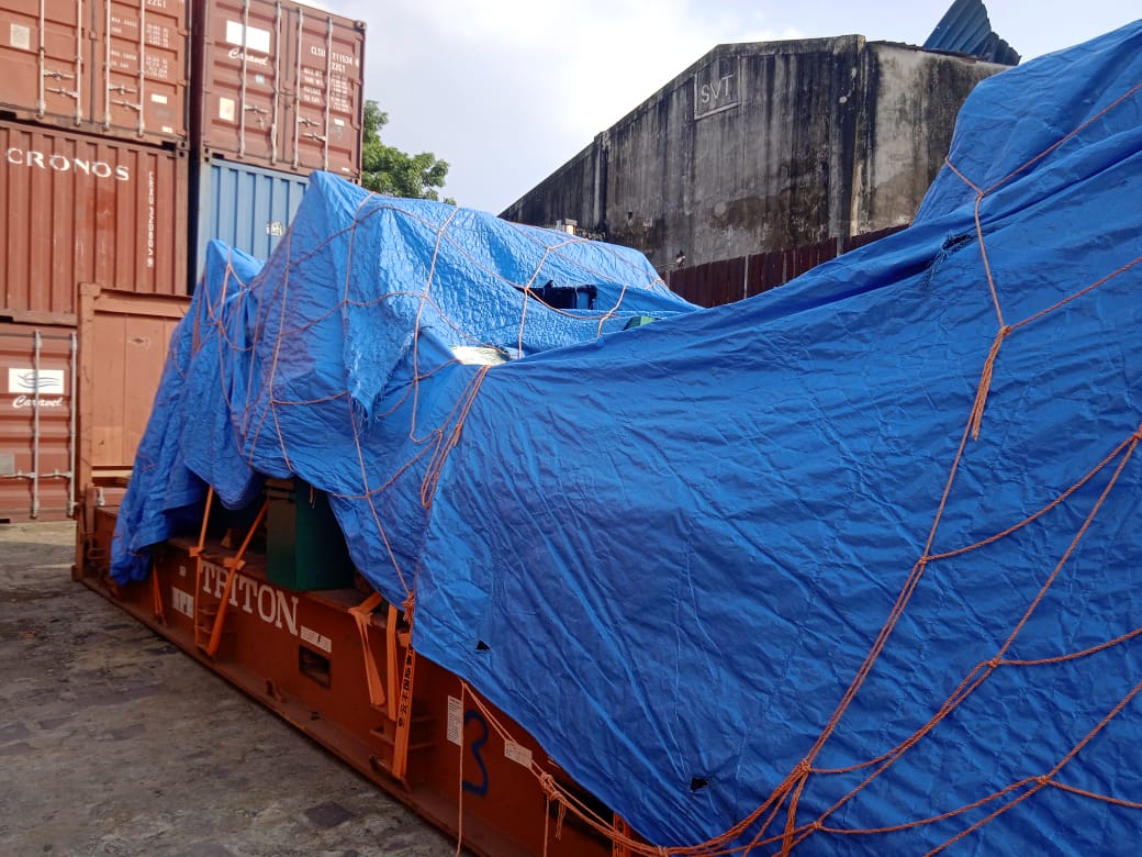 Tarpaulin and rope netting over cargo on a flat-rack container