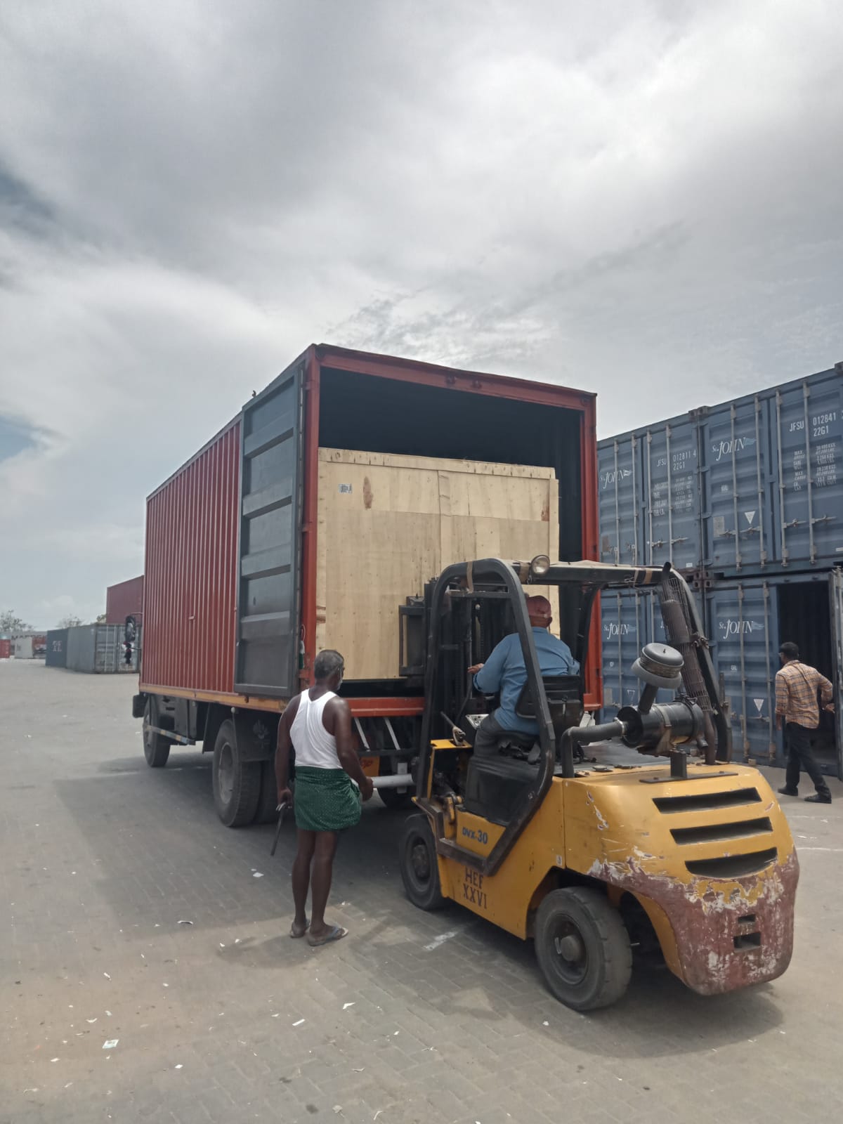 Forklift loading a wooden crate into a container truck