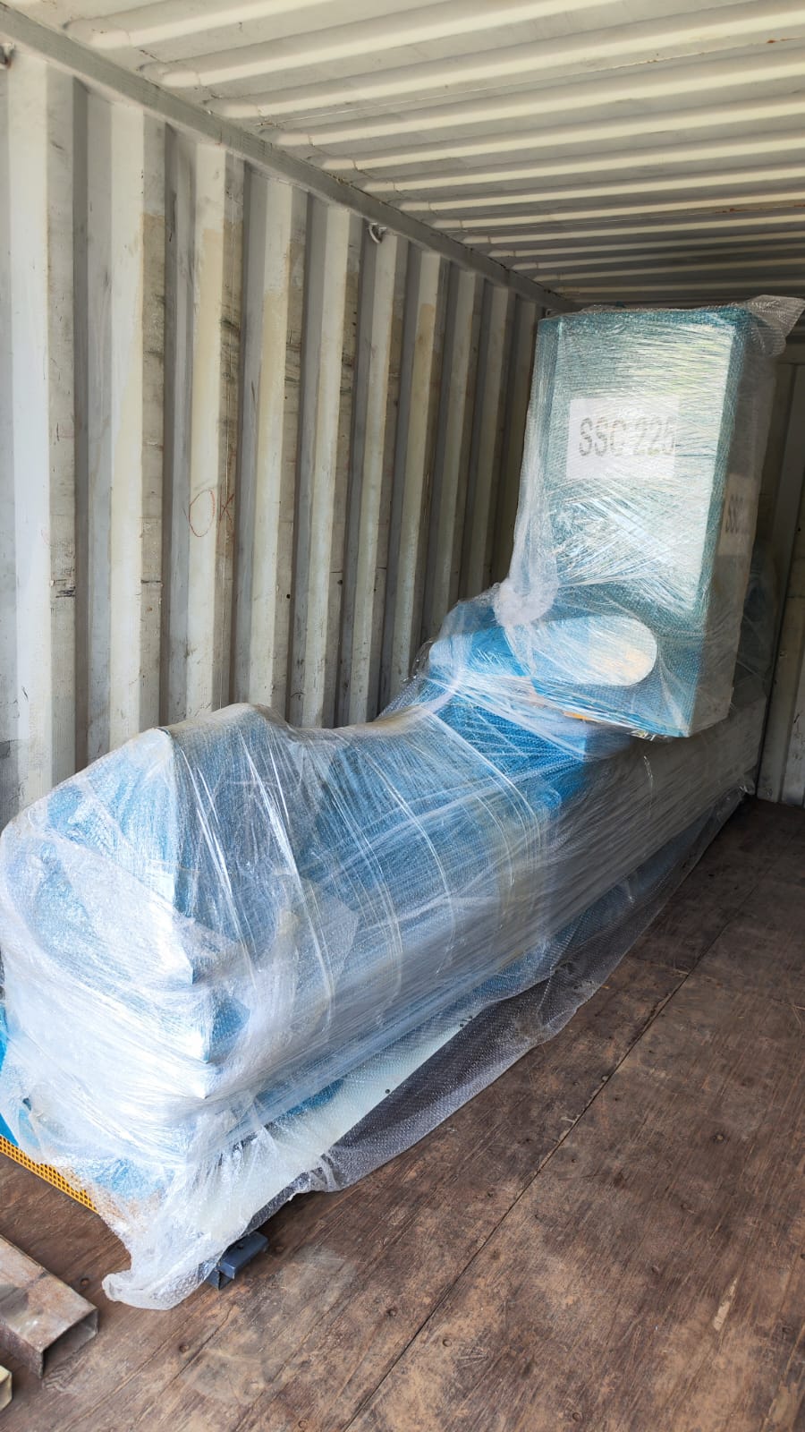 Bubble-wrapped machine loaded along a container wall